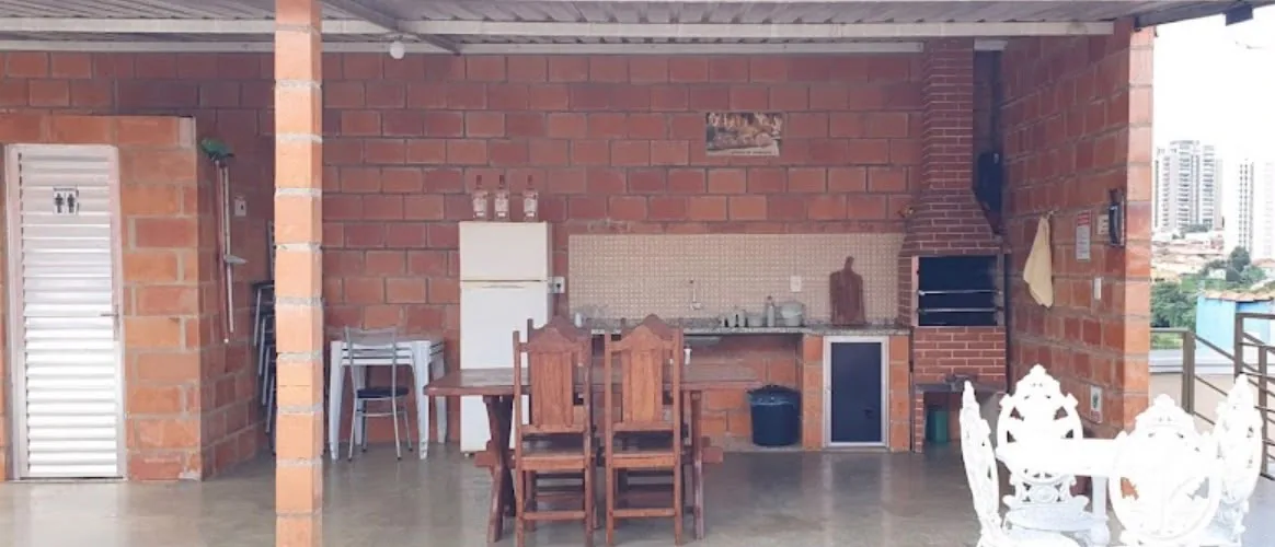 Área comum da pousada com churrasqueira, mesas e cadeiras