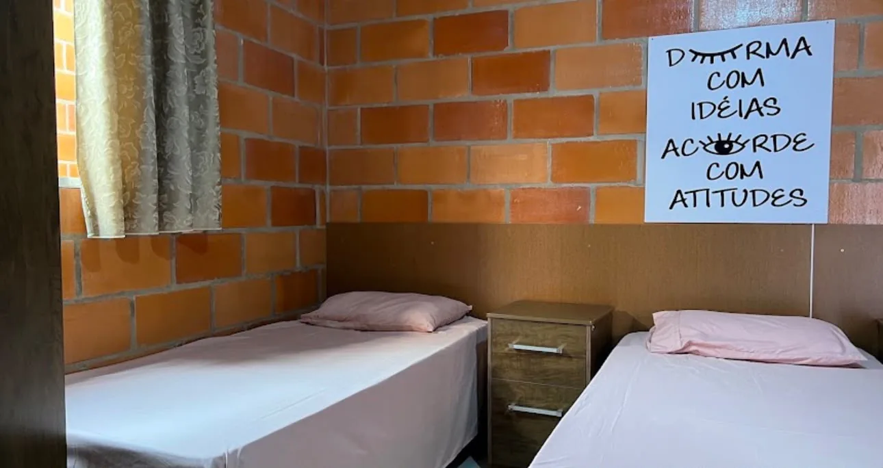 Quarto da pousada com duas camas de solteiro e criado-mudo